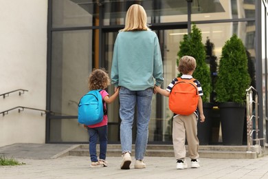 Photo of Woman and her children on their way to kindergarten outdoors, back view