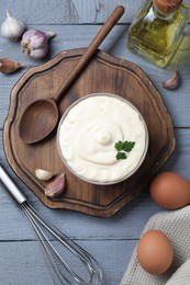 Photo of Tasty mayonnaise in bowl, ingredients and whisk on gray wooden table, flat lay