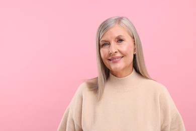 Photo of Portrait of beautiful middle aged woman on pink background, space for text