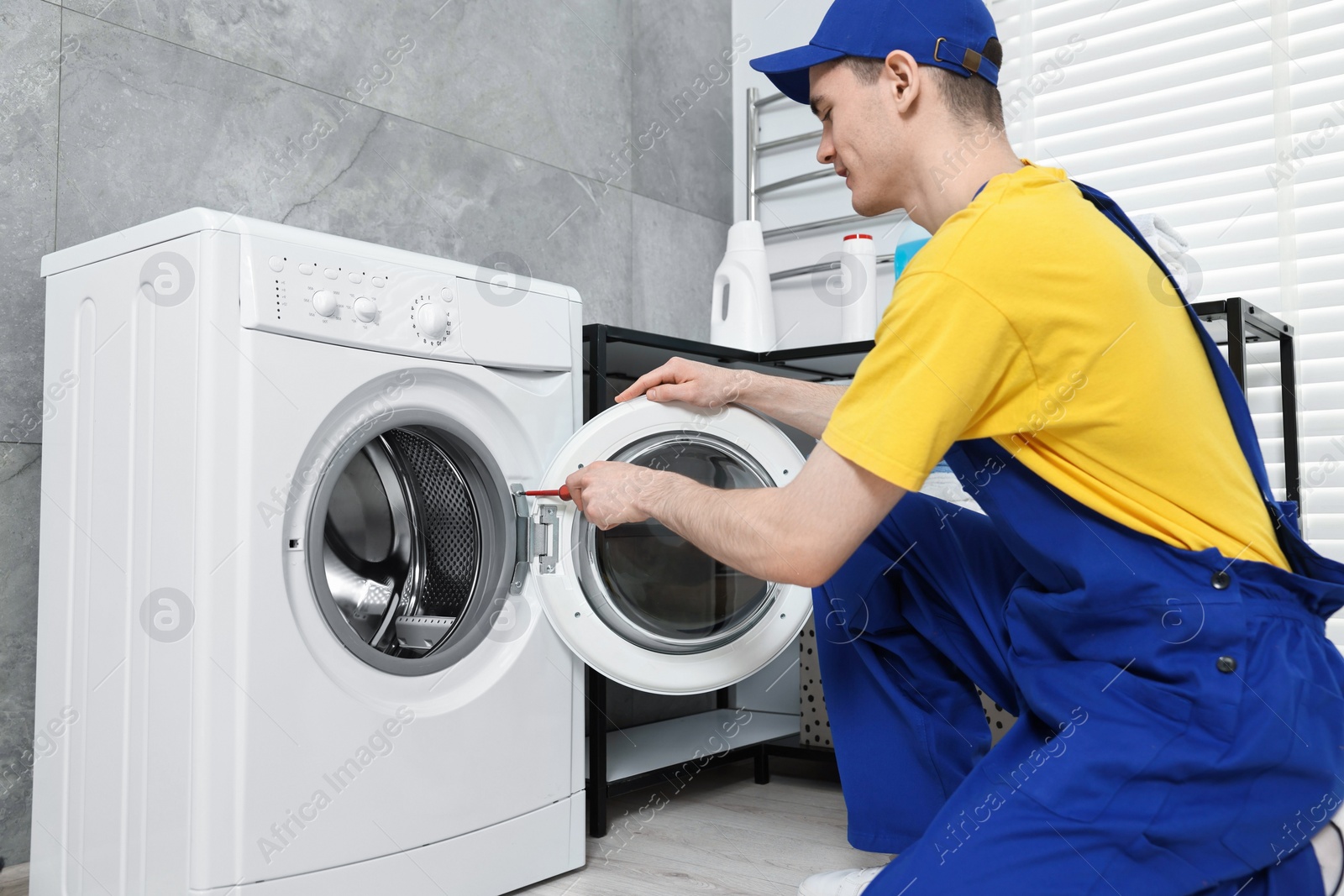 Photo of Plumber repairing washing machine in bathroom, low angle view