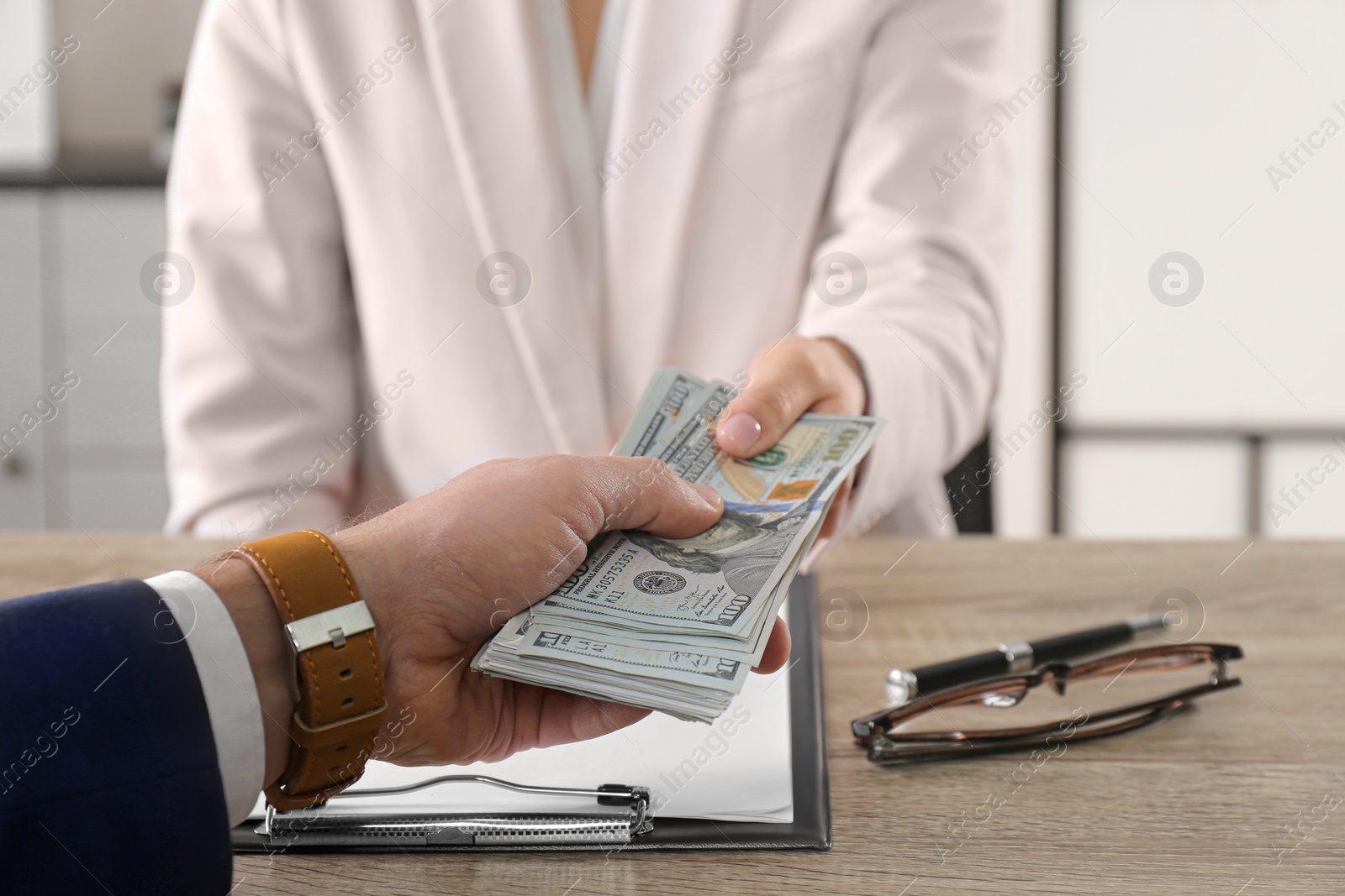 Photo of Man giving bribe to woman at table in office, closeup