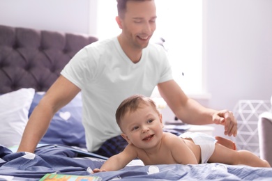 Photo of Young father with his cute little son on bed