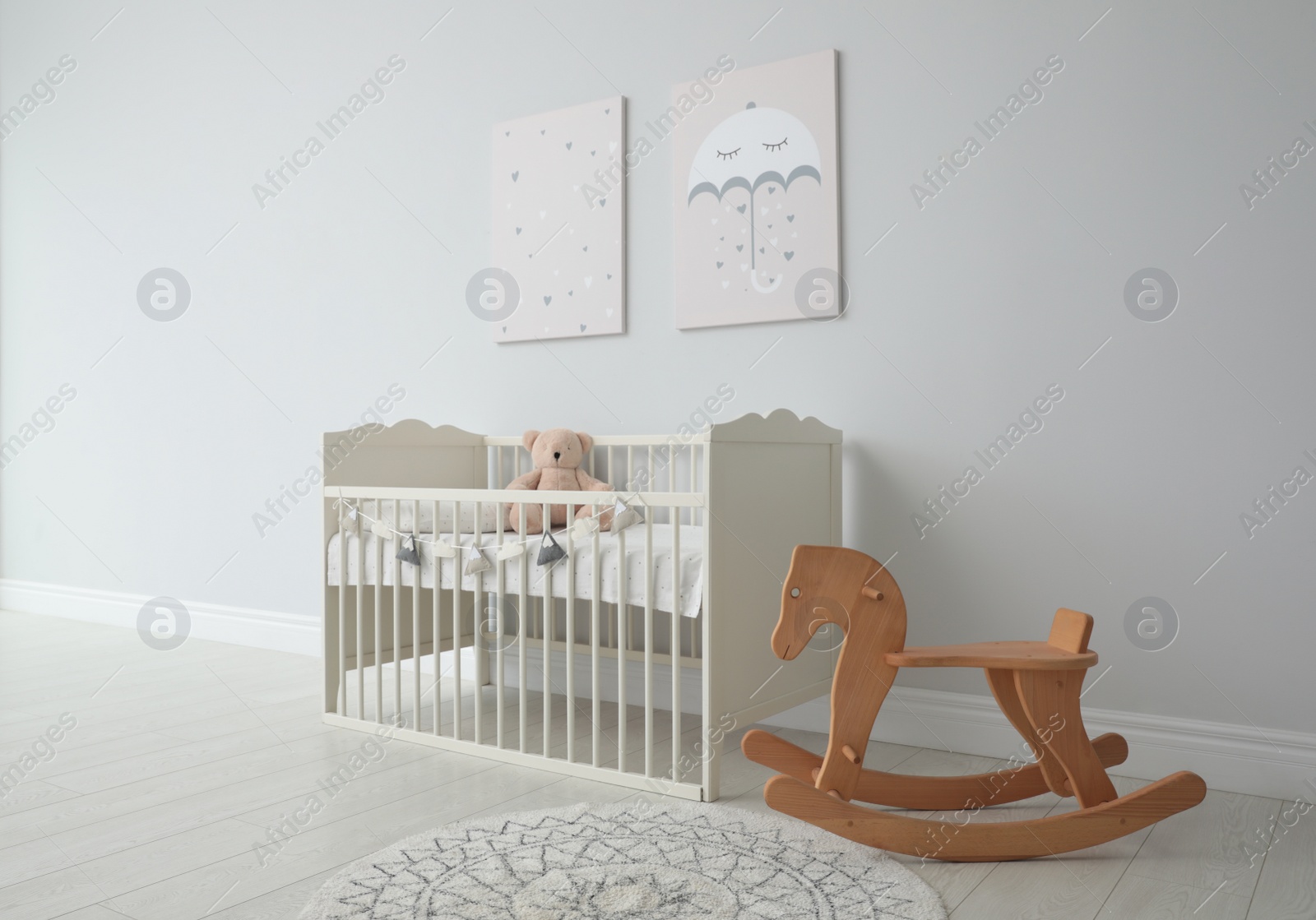 Photo of Minimalist room interior with baby crib, decor elements and toys