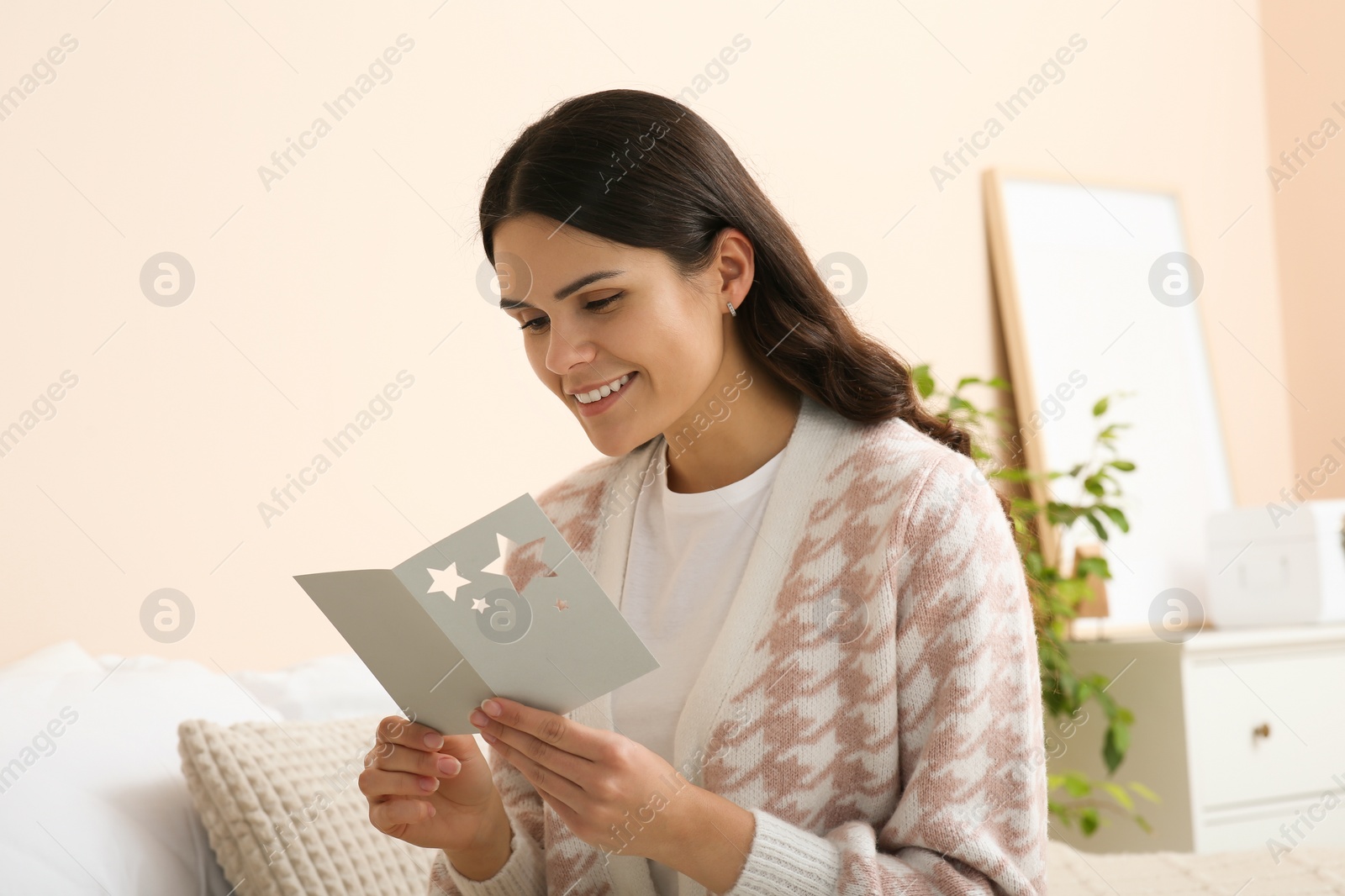 Photo of Young woman with greeting card in bedroom