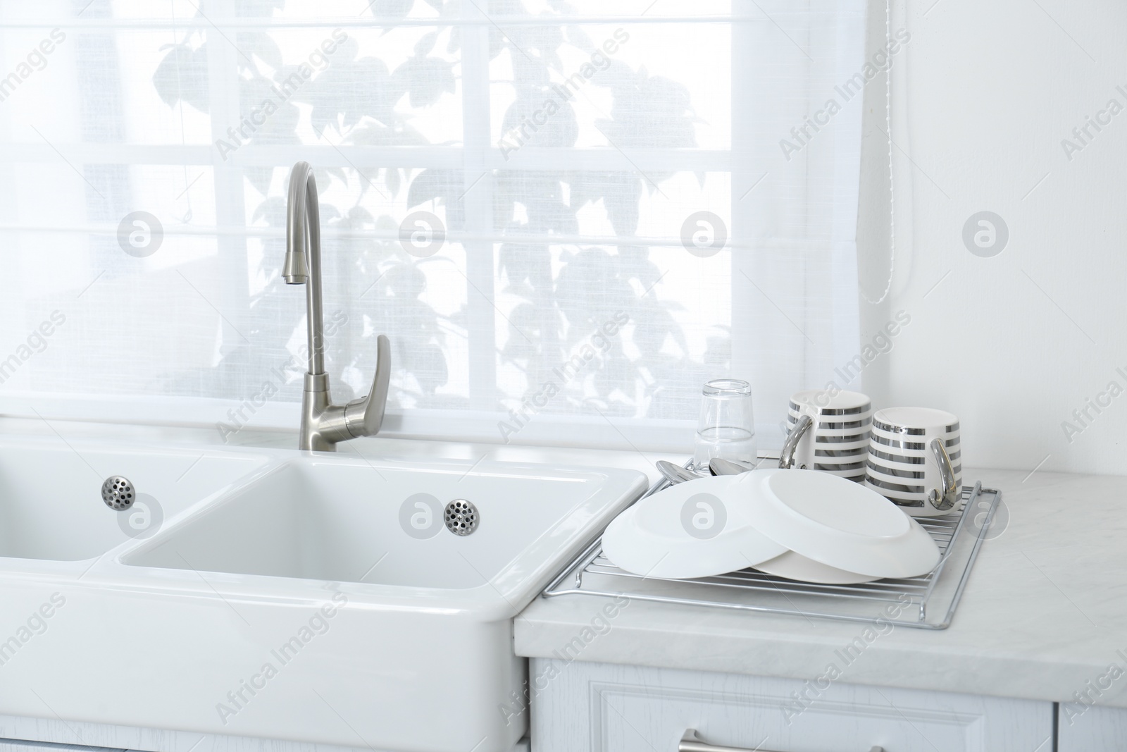 Photo of Clean dishes drying on rack in modern kitchen