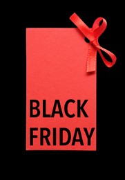 Image of Red tag with phrase BLACK FRIDAY on dark background, top view