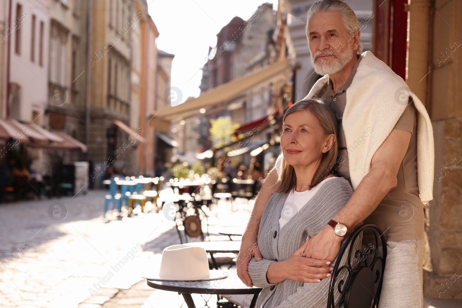 Photo of Affectionate senior couple sitting in outdoor cafe, space for text