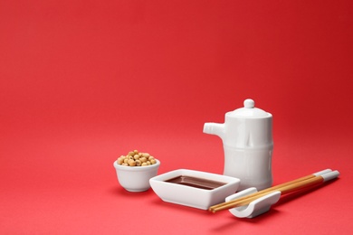 Photo of Tableware with soy sauce and beans on color background. Space for text