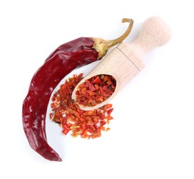 Photo of Aromatic spice. Red chili pepper flakes in scoop and pod isolated on white, top view