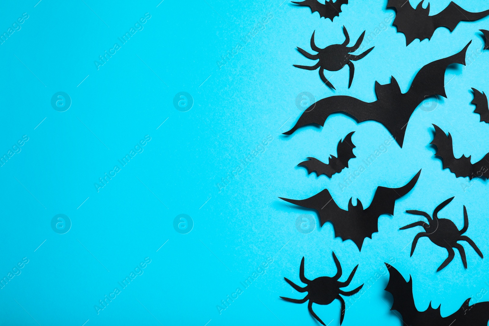 Photo of Flat lay composition with paper bats and spiders on light blue background, space for text. Halloween decor