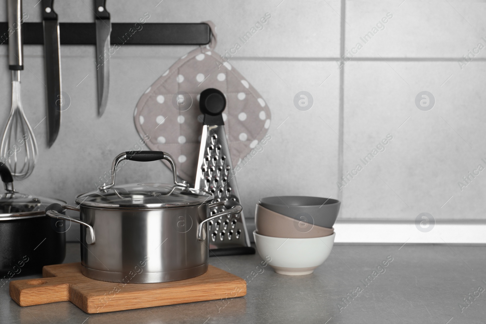 Photo of Cooking utensils and other kitchenware on grey countertop. Space for text