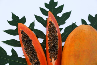 Photo of Whole and cut fresh ripe papaya fruits with leaf on white background, flat lay