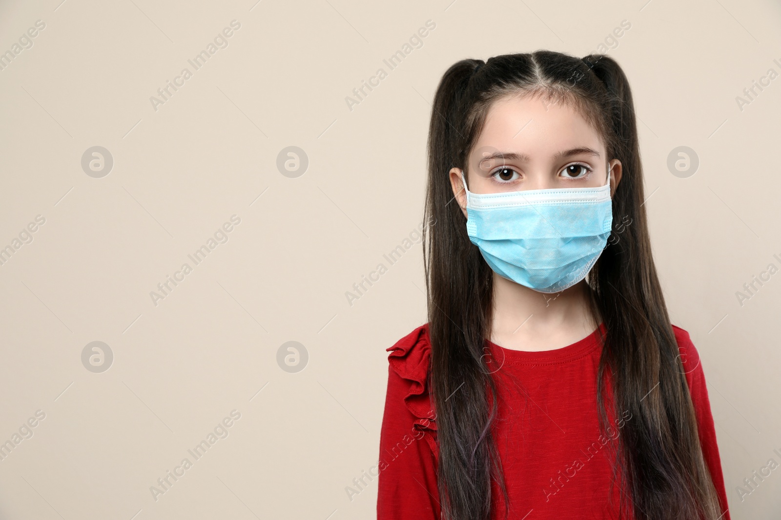 Photo of Little girl in medical mask on beige background, space for text. Virus protection