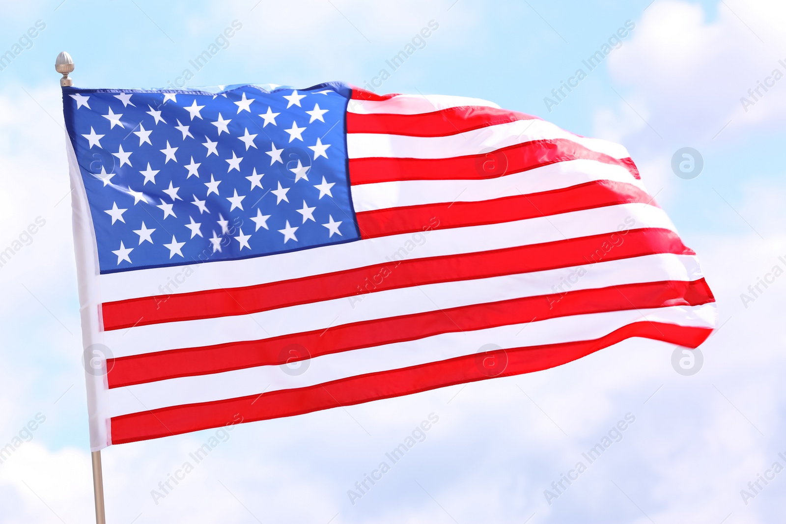 Photo of American flag fluttering outdoors on cloudy day