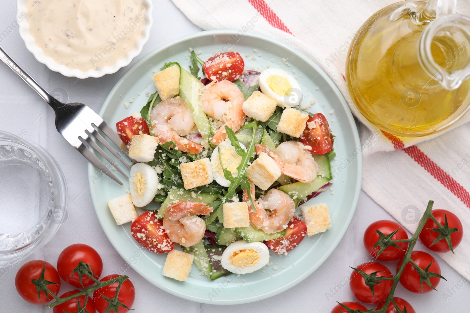 Photo of Delicious Caesar salad with shrimps and ingredients on white table, flat lay