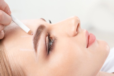 Cosmetologist preparing young woman for  eyebrow permanent makeup procedure, closeup