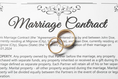 Photo of Marriage contract and gold rings on table, top view