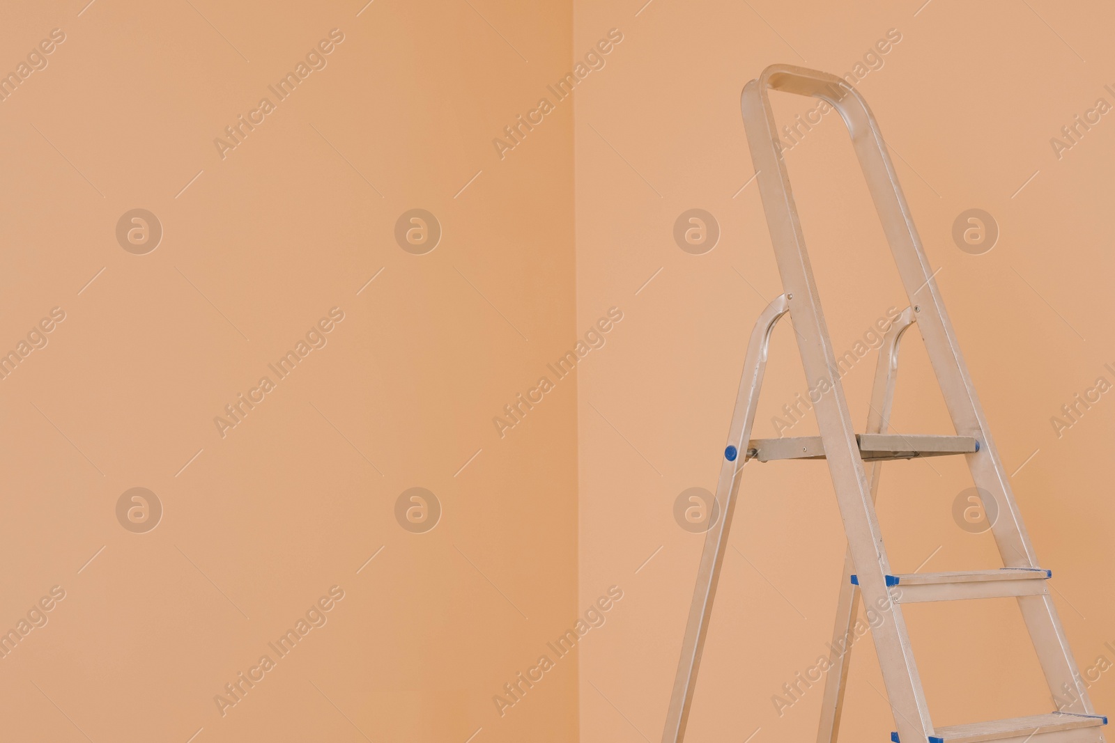 Photo of Ladder near pale orange wall, space for text. Room renovation