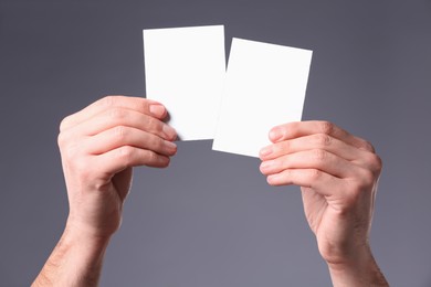 Photo of Man holding paper cards on grey background, closeup. Mockup for design