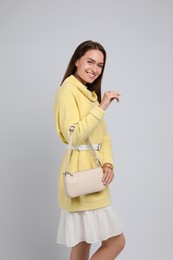 Fashionable young woman with stylish bag on light background