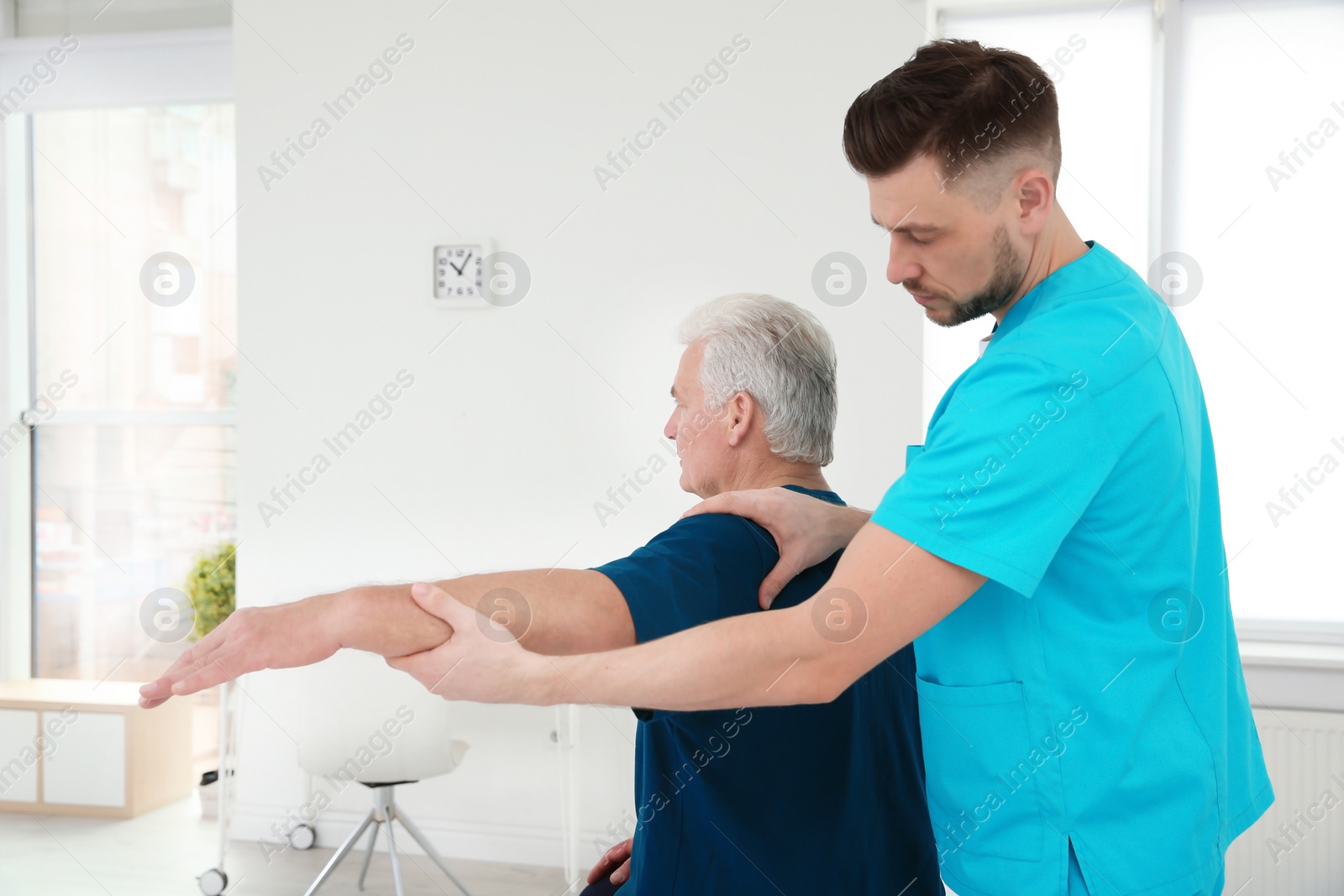 Photo of Young physiotherapist working with senior patient in clinic