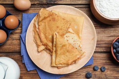 Delicious crepes and ingredients on wooden table, flat lay