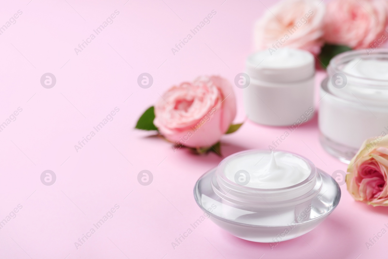 Photo of Jar of organic cream and flower on pink background. Space for text