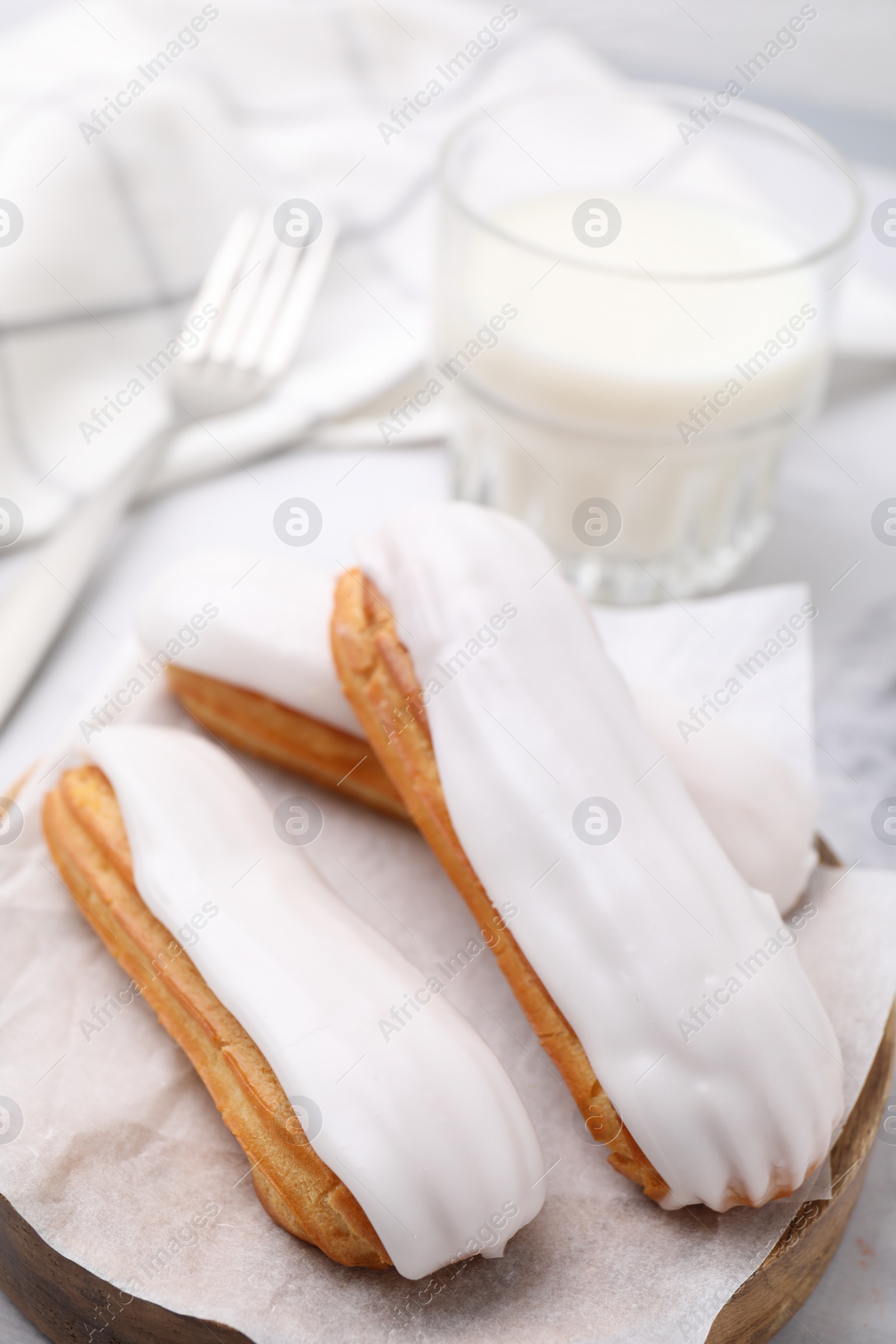 Photo of Delicious eclairs covered with glaze on white table, closeup