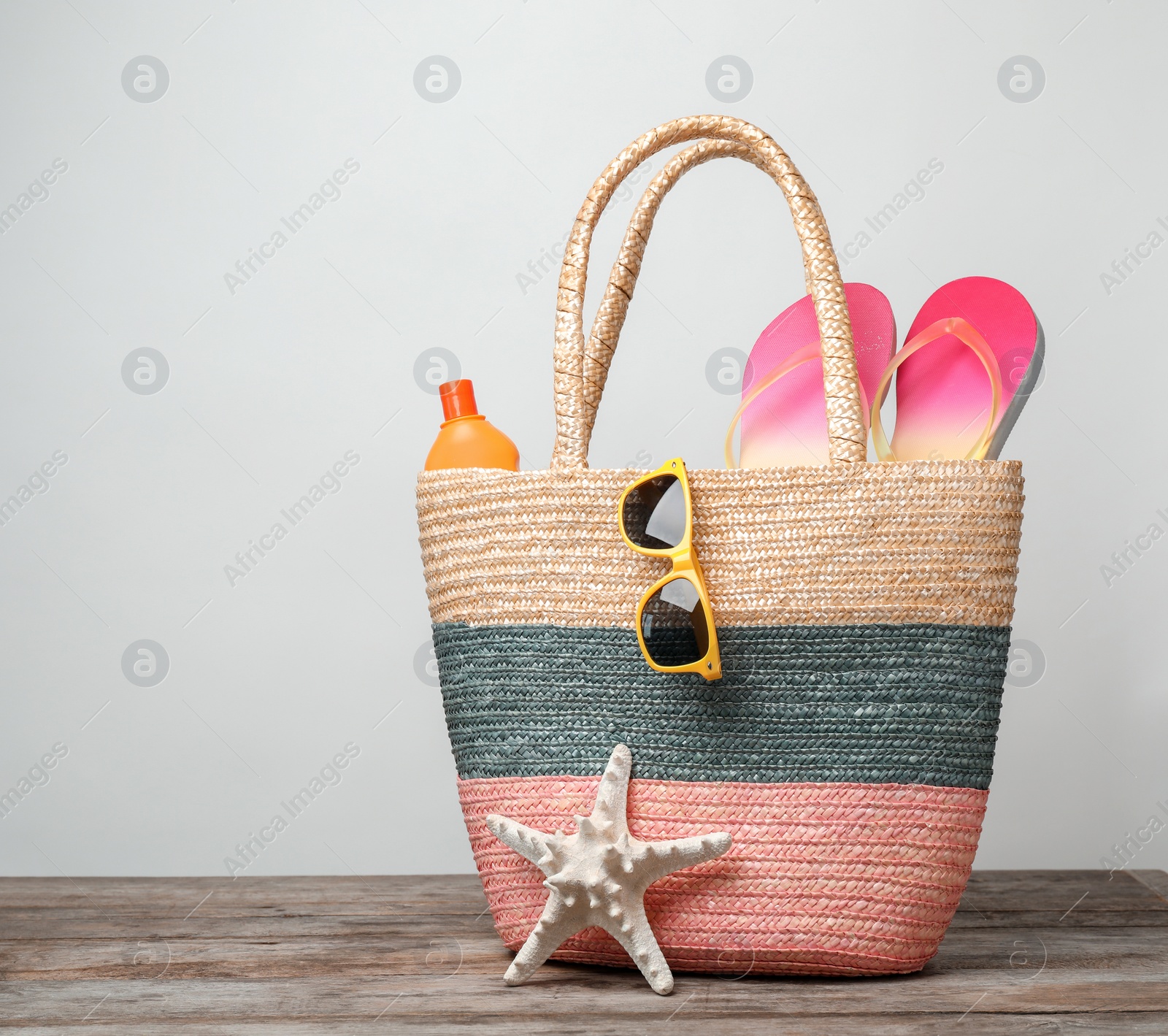 Photo of Bag with beach objects on table against light background