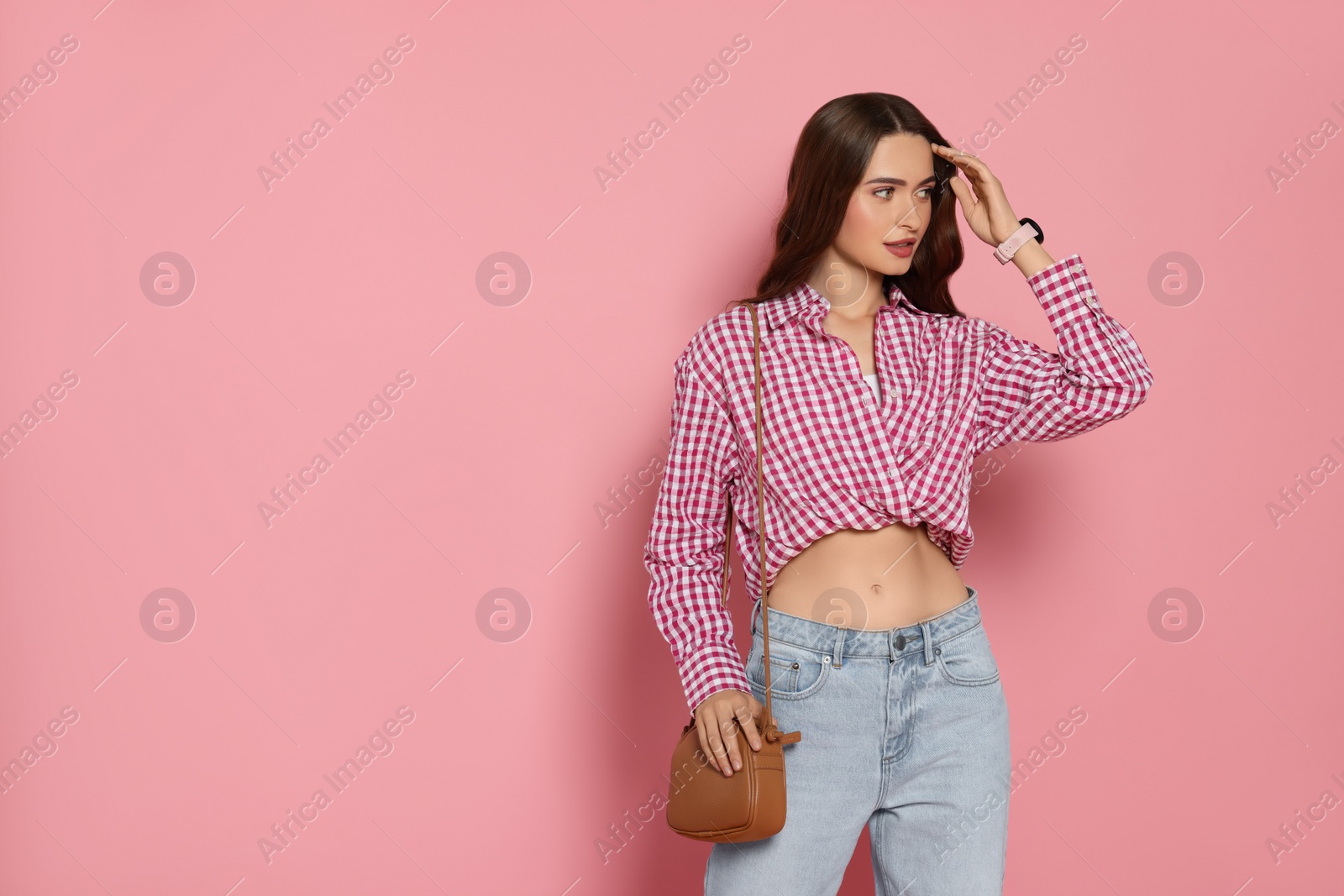 Photo of Beautiful young woman in fashionable outfit with stylish bag on pink background, space for text