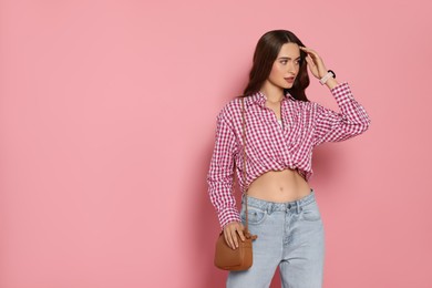 Photo of Beautiful young woman in fashionable outfit with stylish bag on pink background, space for text