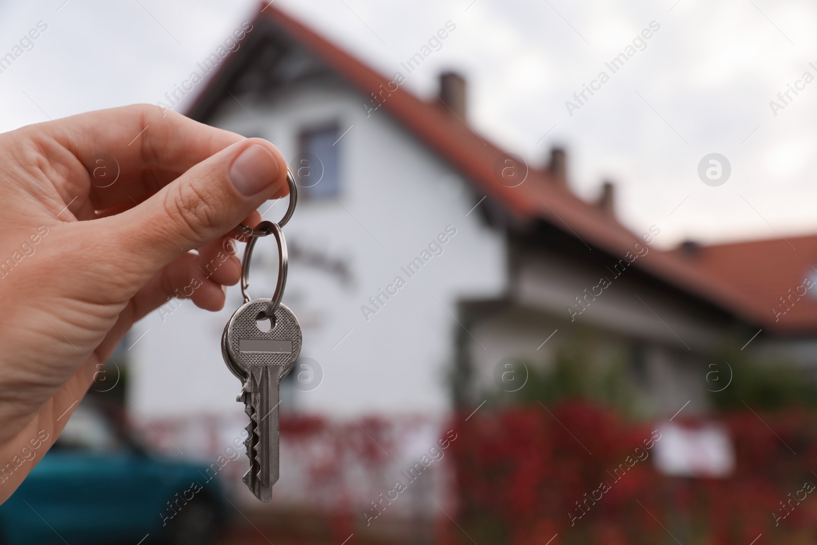 Photo of Real estate agent holding keys to new house outdoors, closeup. Space for text