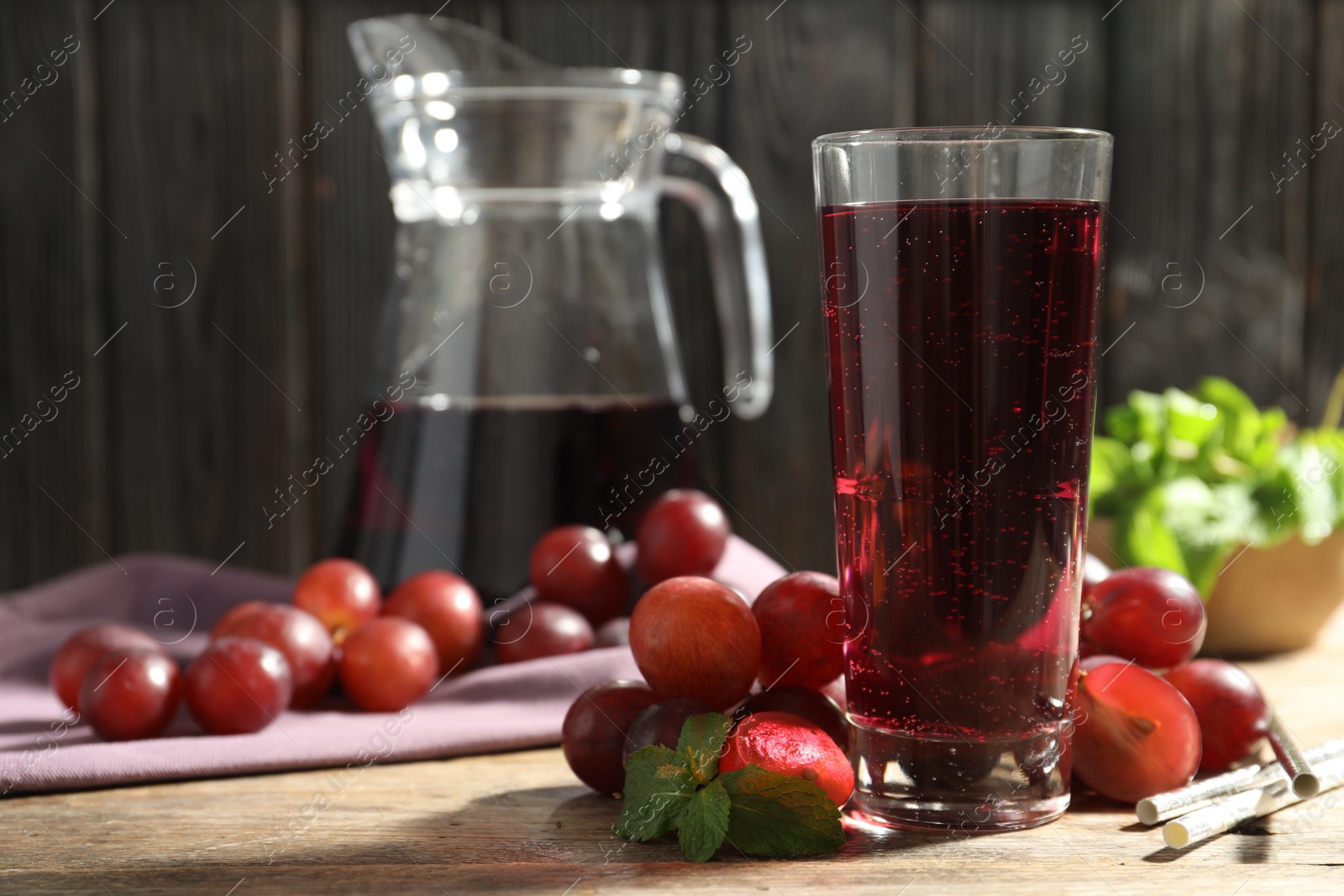 Photo of Delicious grape soda water with mint and berries on wooden table. Refreshing drink