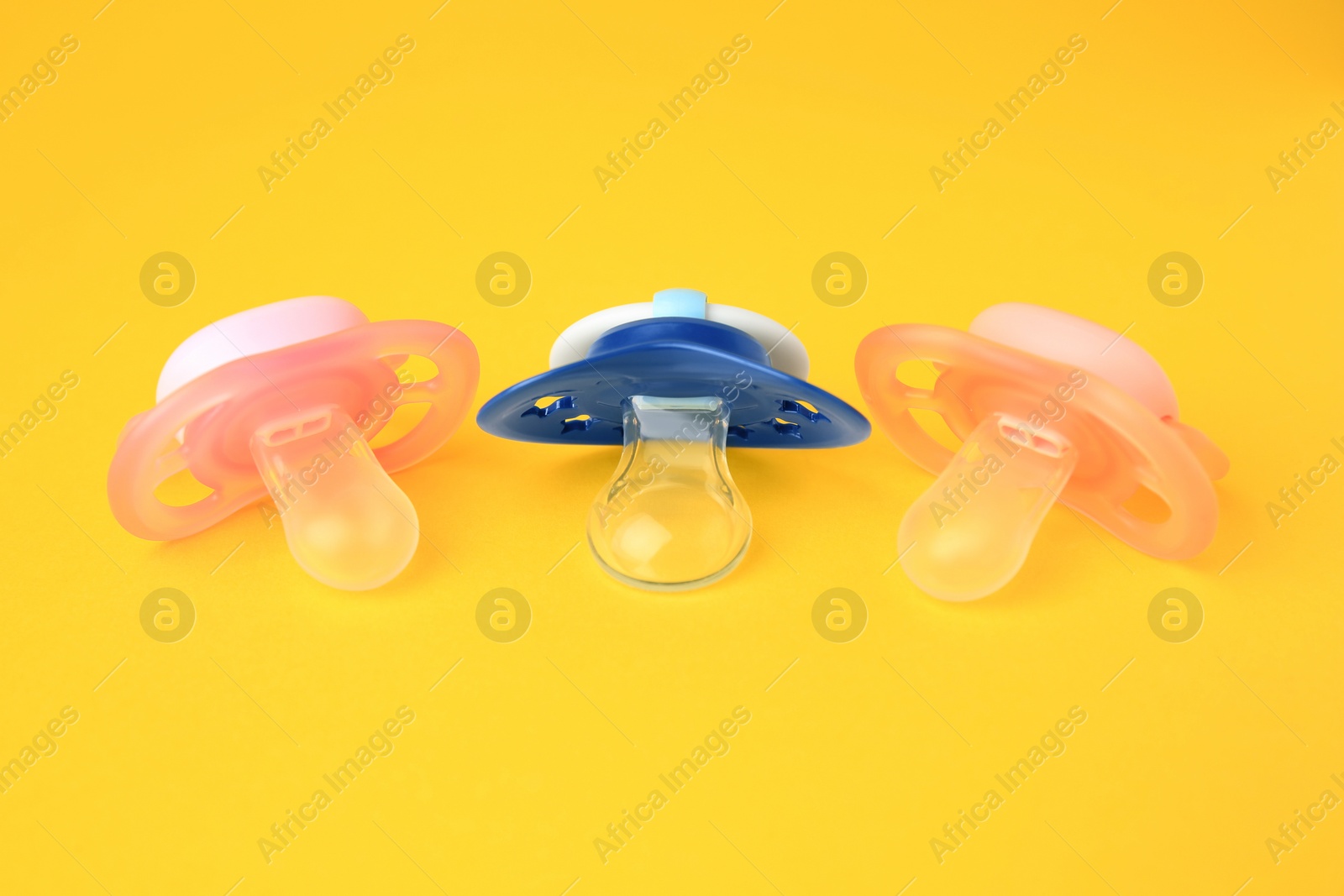 Photo of Colorful baby pacifiers on bright orange background