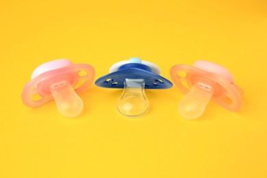 Photo of Colorful baby pacifiers on bright orange background