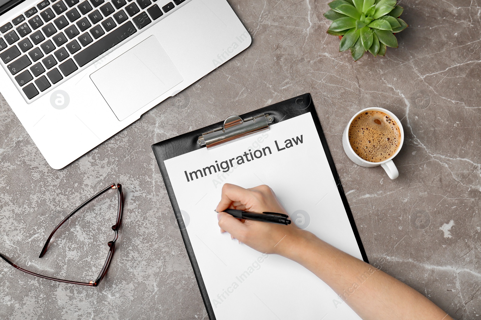 Photo of Woman filling form with words IMMIGRATION LAW at table, top view