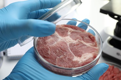 Photo of Scientist holding Petri dish with cultured meat in laboratory, closeup