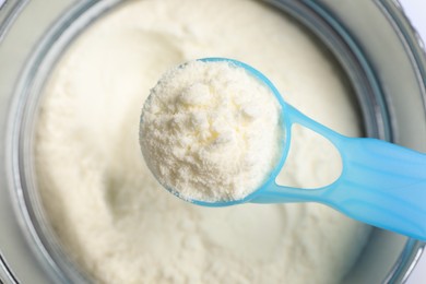Photo of Scoop of powdered infant formula over can, top view. Baby milk