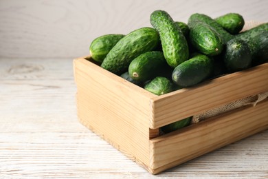 Photo of Crate full of fresh ripe cucumbers on white wooden table