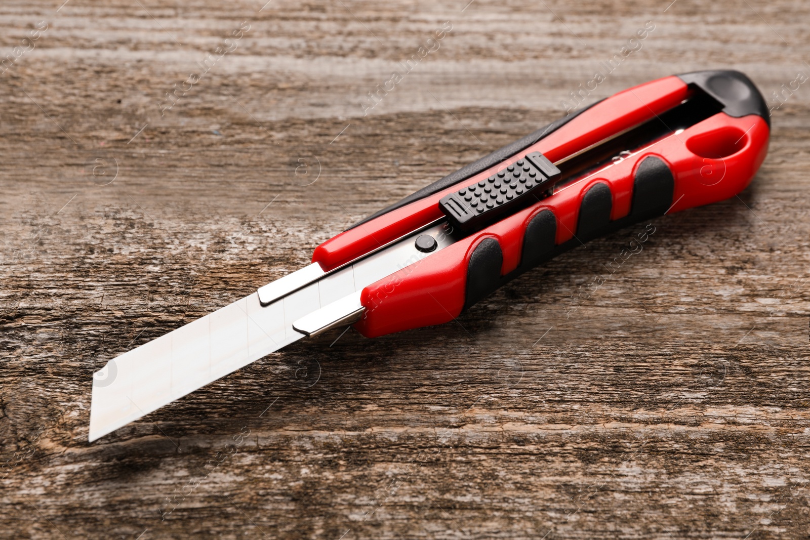 Photo of Utility knife on wooden table. Construction tool