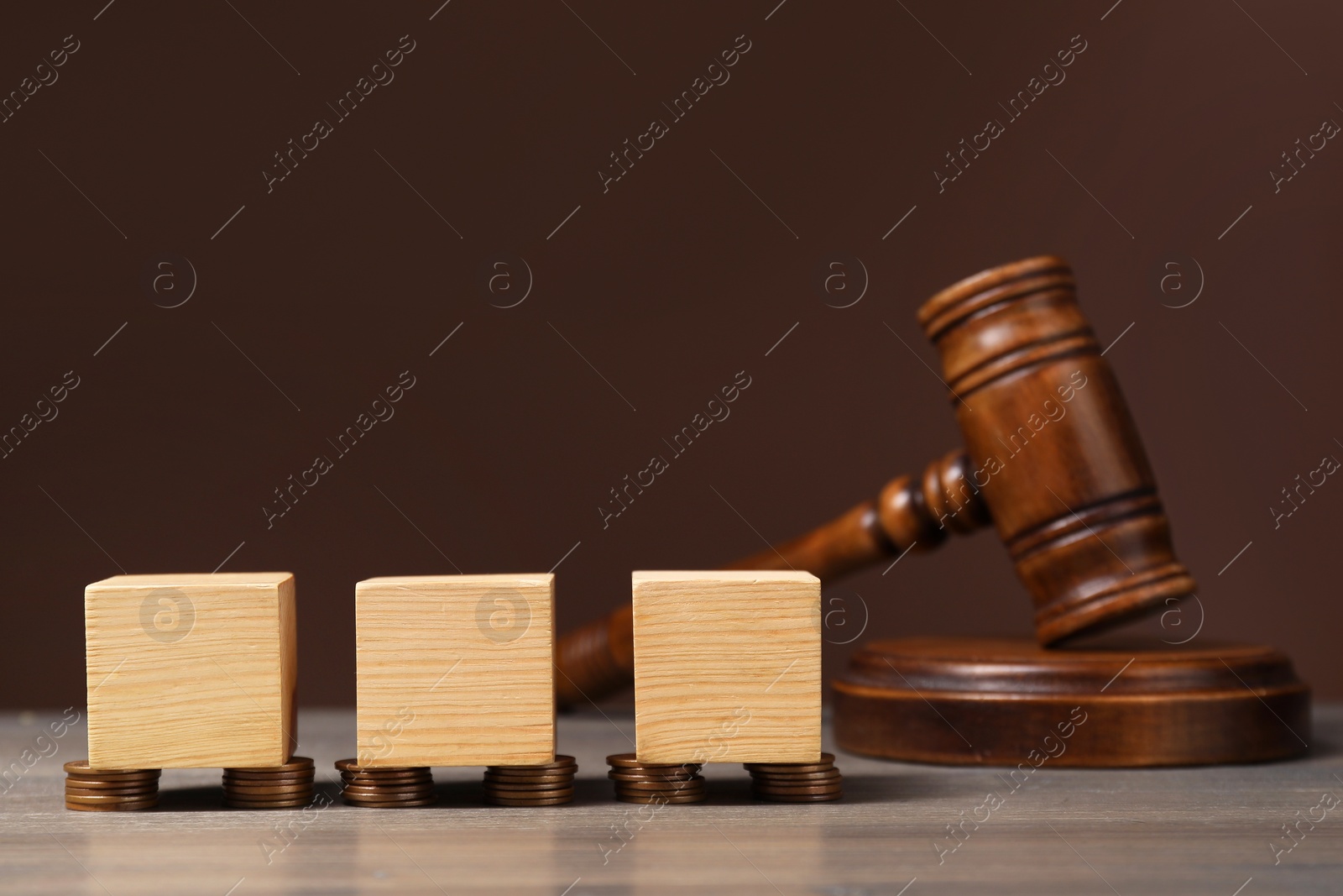 Photo of Law. Blank cubes, coins and gavel on wooden table against brown background, space for text