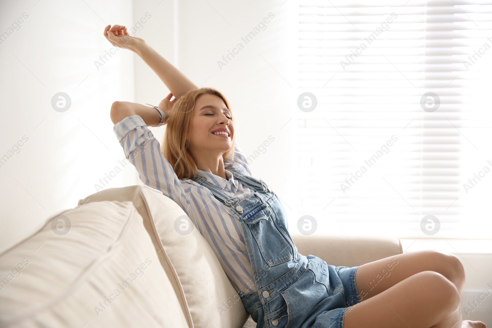 Photo of Young woman relaxing on couch near window at home