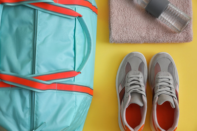 Photo of Gym bag and sports equipment on yellow background, flat lay