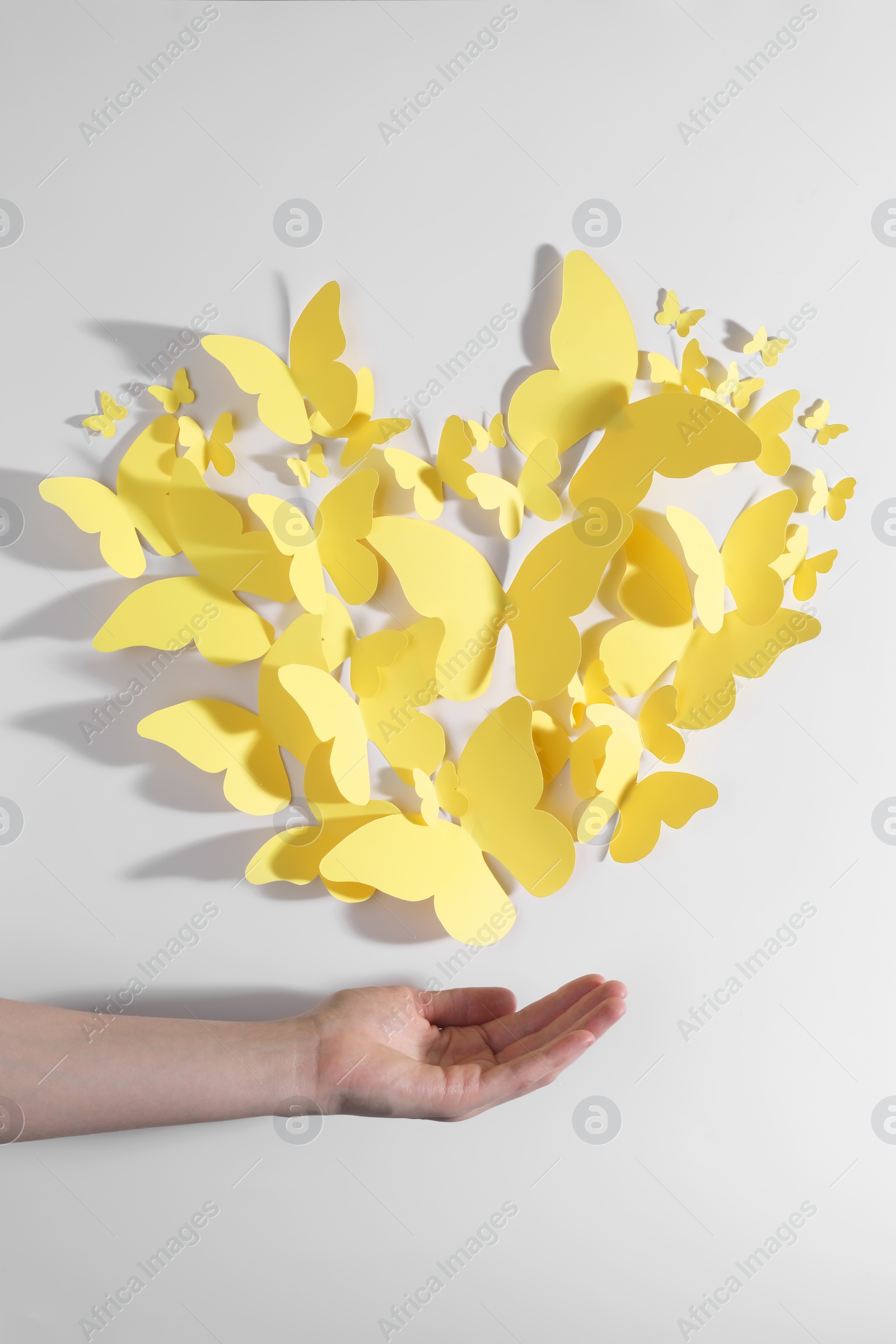 Photo of Woman with yellow paper butterflies on white background, top view