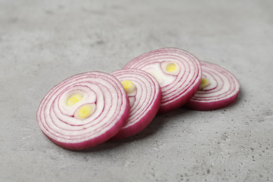 Photo of Slices of red onion on light grey table, closeup