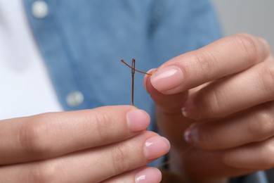 Woman inserting thread through eye of needle, closeup