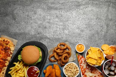 Photo of French fries, burger and other fast food on gray textured table, flat lay with space for text