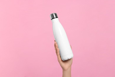 Photo of Woman holding thermo bottle on pink background, closeup
