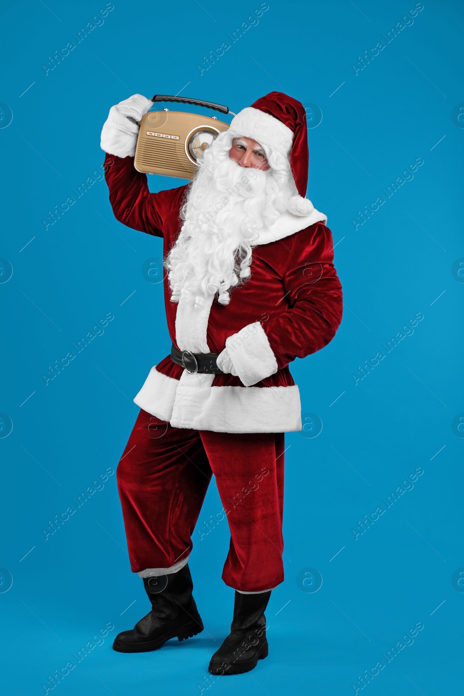 Photo of Santa Claus with vintage radio on blue background. Christmas music