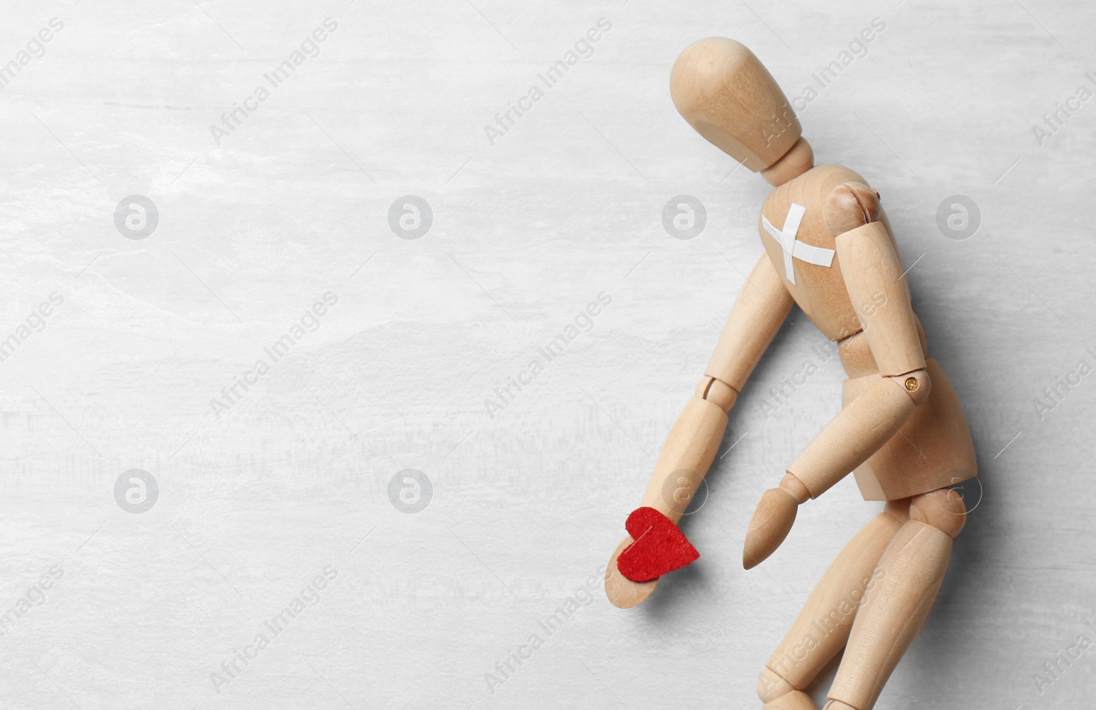 Photo of Wooden puppet holding small heart on gray background, space for text. Relationship problems